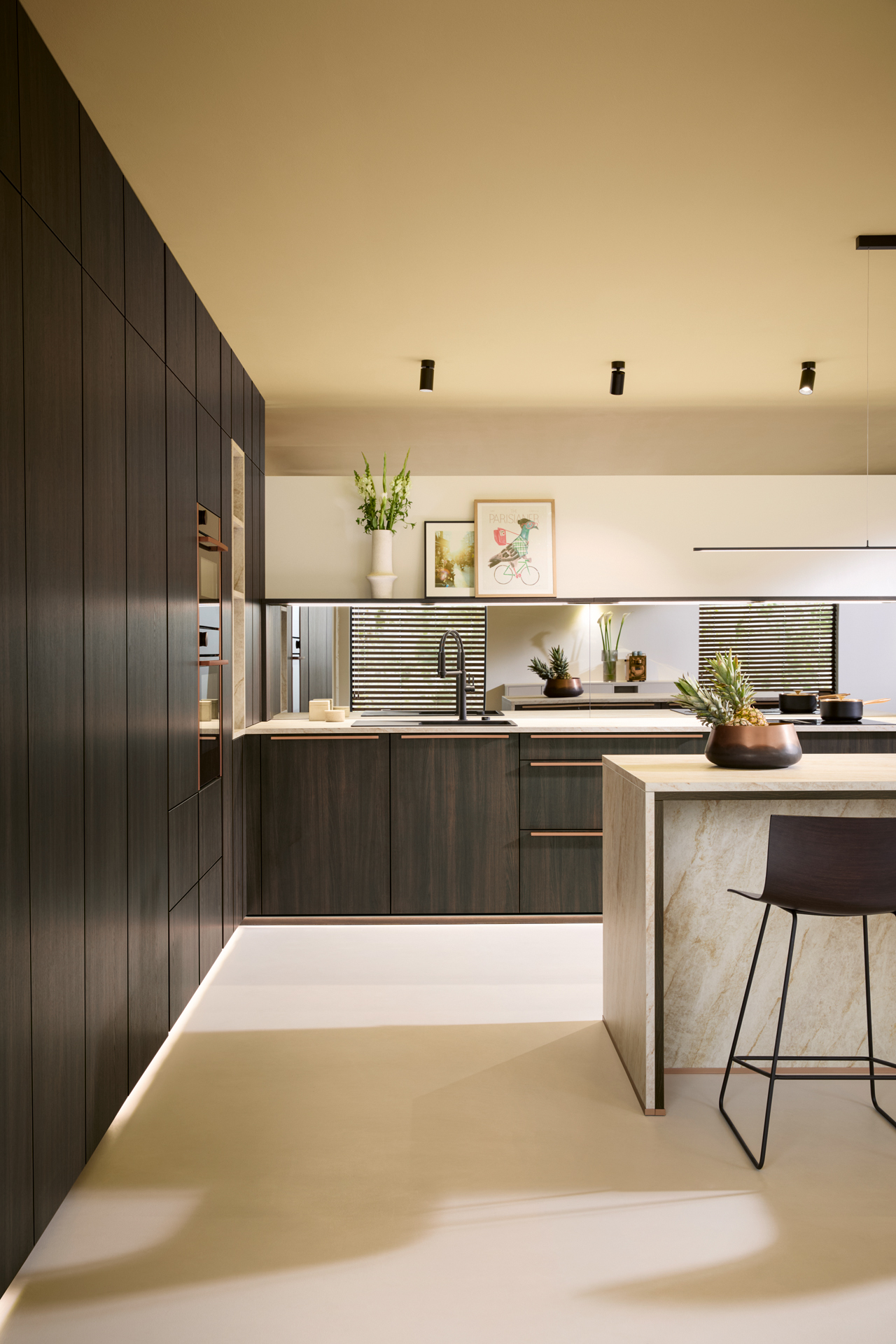 A dark oak Schüller kitchen with a marble island, copper handles and mirrored splashback